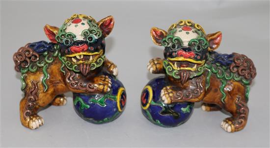 A pair of Chinese polychrome pottery figures of lion-dogs with balls, height 12cm
